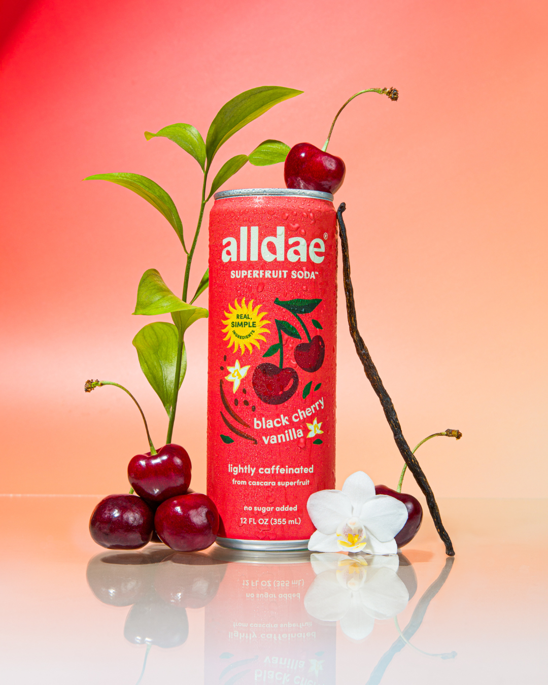alldae superfruit soda Black Cherry Vanilla sits next to real black cherries and real vanilla bean.
